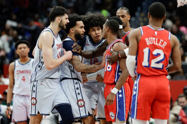 Wizards forward Kyshawn George (center) is held back by teammates after being fouled by Sixers guard Lonnie Walker IV (right). Walker picked up a Flagrant 1 foul.