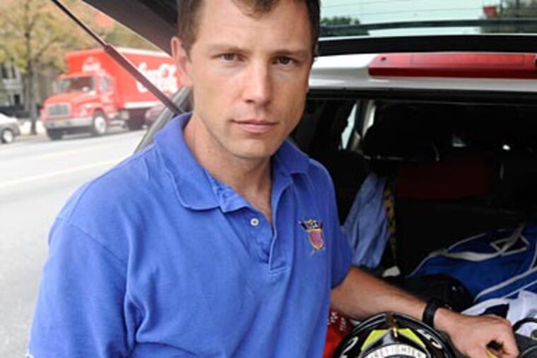 Temple women's rowing coach Jason Read poses with the helmet of the Hopewell Fire Department. (Ron Tarver/Staff Photographer)