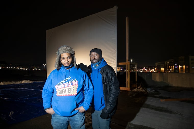 A pop-up drive-in theater is being set up by Parking Lot Theaters on the upper level of the Exton Mall parking garage on Feb. 10, 2021. They will be showing movies on weekend nights, beginning Friday. Jason Hunter, left, the company's founder, and Dan Chattin are shown in front of the screen.