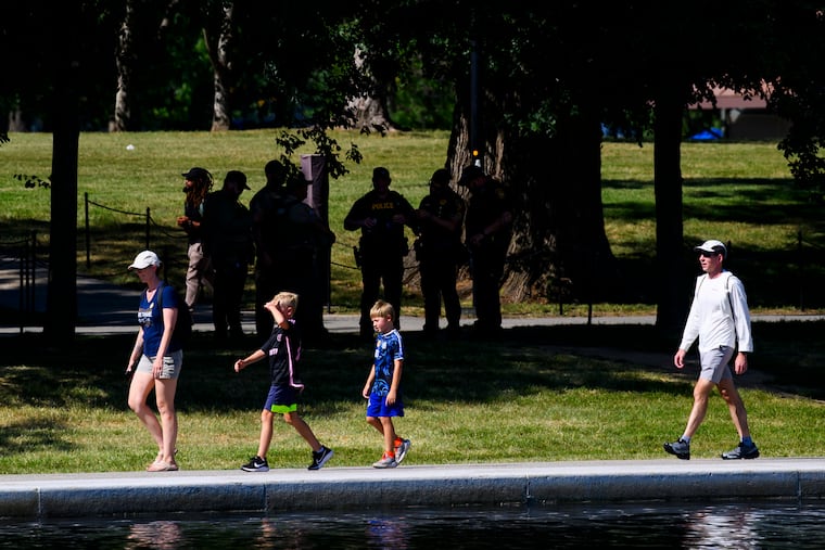 Visitors walk along the Reflecting Pool on Sunday as law enforcement officers are seen in the background.