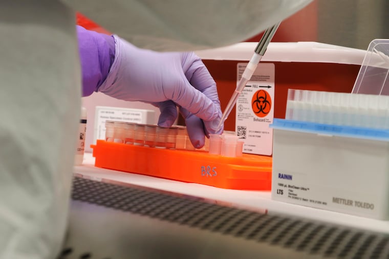 In this March photo, Hawaii state Department of Health microbiologist Mark Nagata demonstrates the process for testing a sample for coronavirus at the department's laboratory in Pearl City, Hawaii. An analysis shows that some of the least-populated states, such as Hawaii, with relatively few coronavirus cases received an outsized proportion of the $150 billion in federal money that was designed to address virus-related expenses.