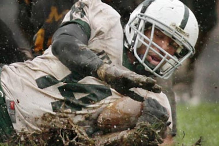 Camden Catholic's Jarred Alwan slides through the mud after being tackled. (Elizabeth Robertson/Staff Photographer)