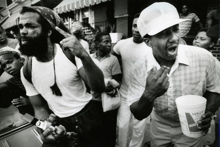 MOVE supporter Michael Jon (left) defends the radical group to Osage Ave. residents as neighbor Wayne Renfro (right) complains about how MOVE activities needlessly endanger the neighborhood.