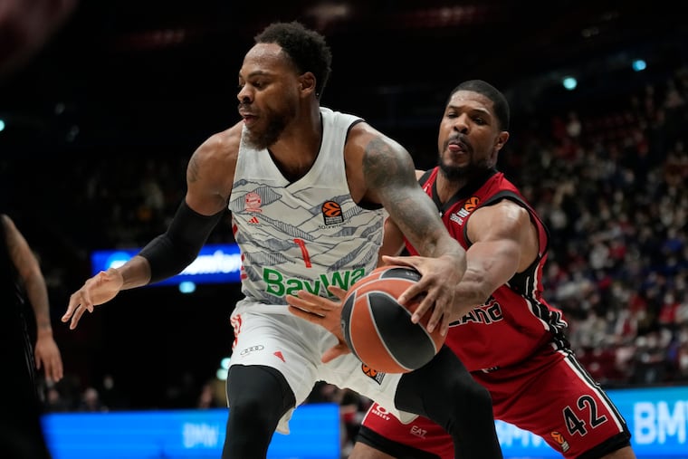 Olimpia Milan's Kyle Hines (right) swipes for the ball as Deshaun Thomas drives toward the basket during a game.