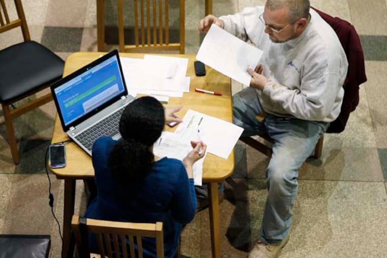 Tiffany Metts (left), a navigator with Resources for Human Development, helps John Brannigan, 48, apply for insurance through the Affordable Care Act. Brannigan, a self-employed construction worker said he got medical and dental insurance for under $200 a month. Resources for Human Development was at the Free Library of Philadelphia helping people apply online. ( MICHAEL S. WIRTZ / Staff Photographer ) March 28, 2014.