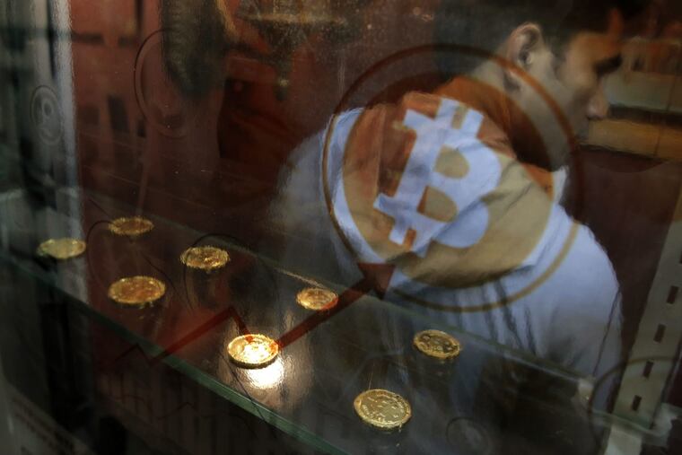 In this Friday, Dec. 8, 2017, file photo, a man uses a Bitcoin ATM in Hong Kong. Bitcoin is the world's most popular virtual currency. Bitcoin and other cryptocurrencies have been plunging.