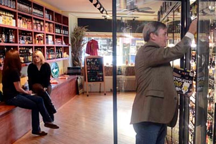 The Greeks owner Drew Johnson grabs some individual bottled beers in the restaurant/bar's adjacent craft beer store in downtown Narberth.