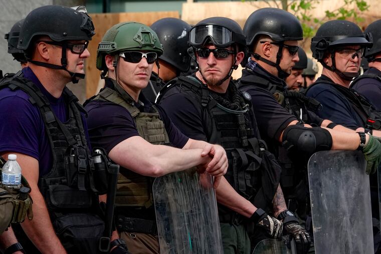 Federal officers block 16th Street near the White House on Wednesday, many wearing uniforms that don't show any identification.