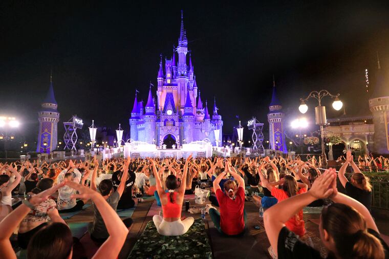 On the morning of the summer solstice, Walt Disney World cast members stretch at Cinderella Castle in the Magic Kingdom, in Lake Buena Vista, Fla., in a pre-dawn gathering before the park opened last week for their annual team yoga session to commemorate International Yoga Day.