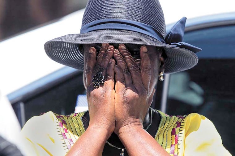 Roselyn Gray, God Mother to the twins who died in a row home fire early Saturday, covers her face after meeting with the media on 6500 block of Gesner Street in Southwest Philadelphia on Sunday, July 6, 2014. ( YONG KIM / Staff Photographer )