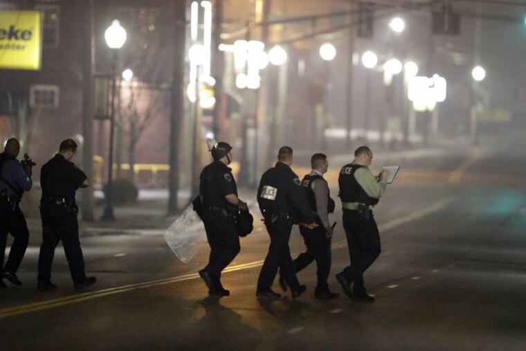 Police canvass the area as they investigate the scene where two police officers were shot outside the Ferguson Police Department Thursday, March 12, 2015, in Ferguson, Mo. (AP Photo/Jeff Roberson)