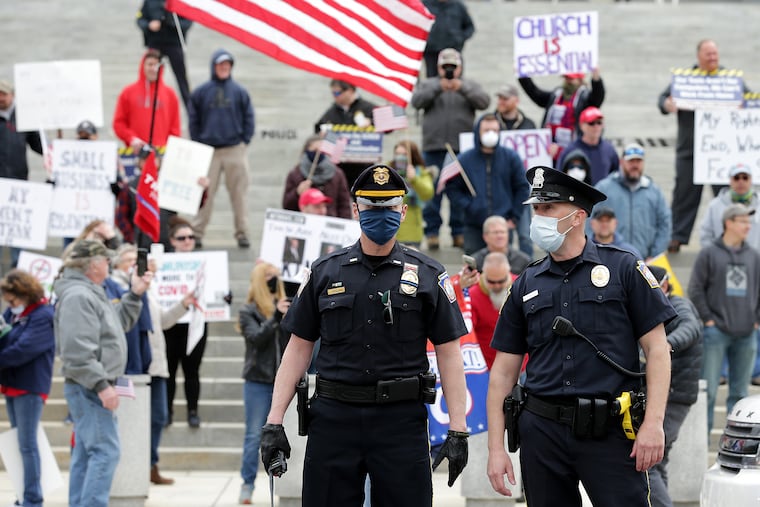 Police direct traffic as protesters gather Monday outside the Pa. capitol in Harrisburg Monday. No citations were issued to protesters who broke the state's stay-at-home order, Capitol Police said.