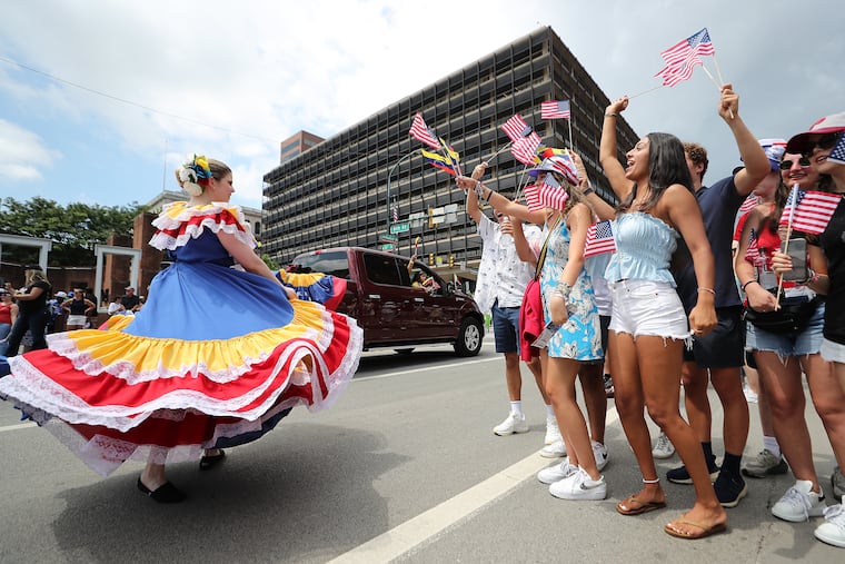 Parade goers watch as a Venezuelan dancer performs during the Wawa Welcome America Salute to Independence Day Parade.