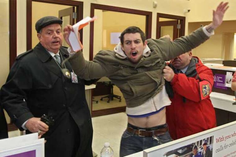 Occupy Philadelphia protester Michael Blas is held by a police officer during a protest by the group at a Wells Fargo Bank office in November 2011. (Michael Bryant / Staff Photographer)