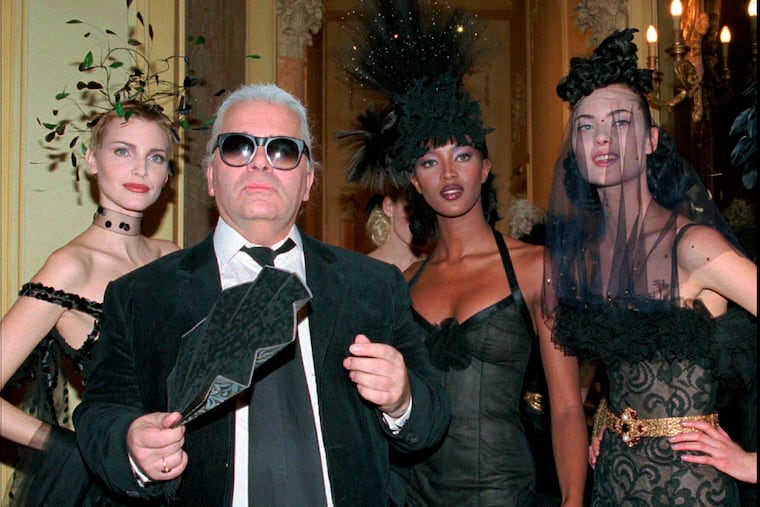 FILE - In this Tuesday January 23, 1996 file photo, German fashion designer Karl Lagerfeld, with fan, stands with German model Nadja Auermann, left, British model Naomi Campbell, second right, and an unidentified model after the presentation of Chanel's 1996 spring/summer haute couture collection, in Paris. Chanel's iconic couturier, Karl Lagerfeld, whose accomplished designs as well as trademark white ponytail, high starched collars and dark enigmatic glasses dominated high fashion for the last 50 years, has died. He was around 85 years old. (AP Photo/Lionel Cironneau, File)