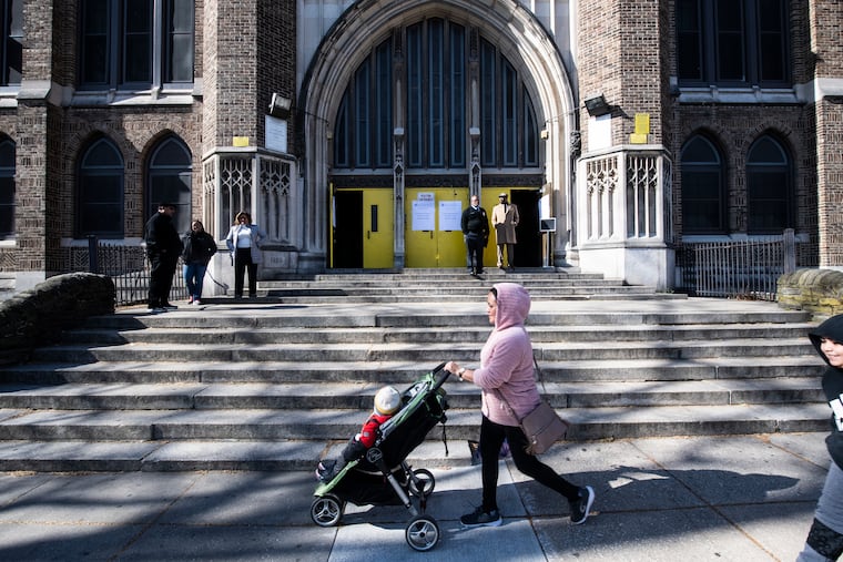 An unidentified mother and child walk in front of Tilden Middle School where families of Philadelphia students had the opportunity to pick up packed breakfast and lunch meals during the two-week school closure. Monday, March 16, 2020.