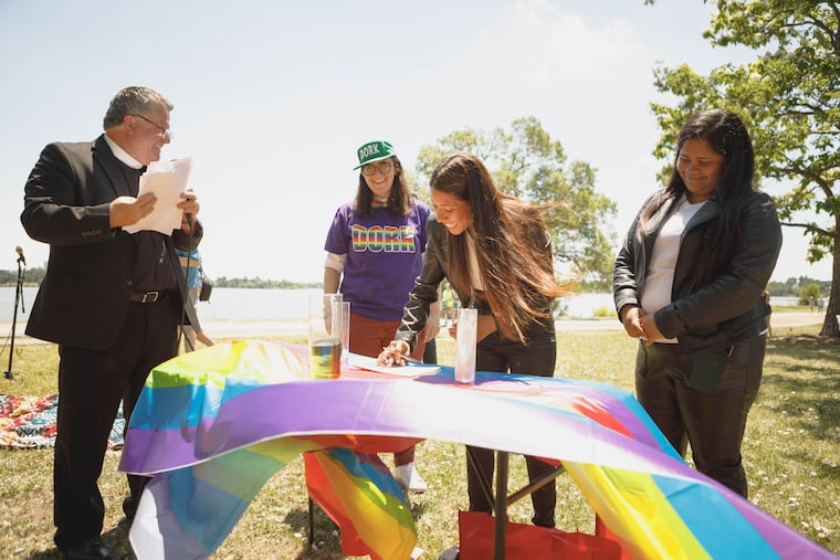 Amarilis Marte signs her marriage certificate on June 9, 2024, at Sloan's Lake Park in Denver with her wife, Mariangy Delgado Gutiérrez (right). The Rev. Quirino Cornejo and Susan Law of Dork Dancing look on.