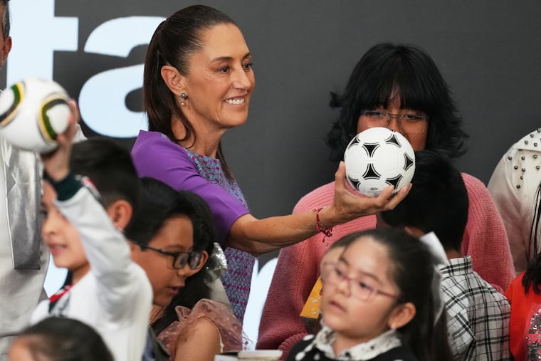Mexican President Claudia Sheinbaum gives a soccer ball to children after her daily morning press conference at the National Palace in Mexico City, Thursday, April 30, 2026.
