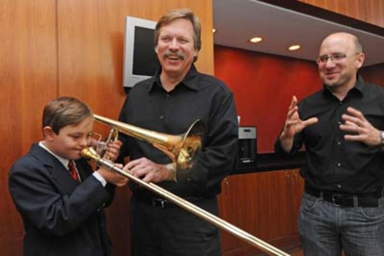 After a performance backstage at the Kimmel Center, trombonists Matt Vaughn, right; and Blair Bollinger greet Aidan Milligan, 9, of Drexel Hill. on Oct. 26, 2012. APRIL SAUL / Staff Photographer
