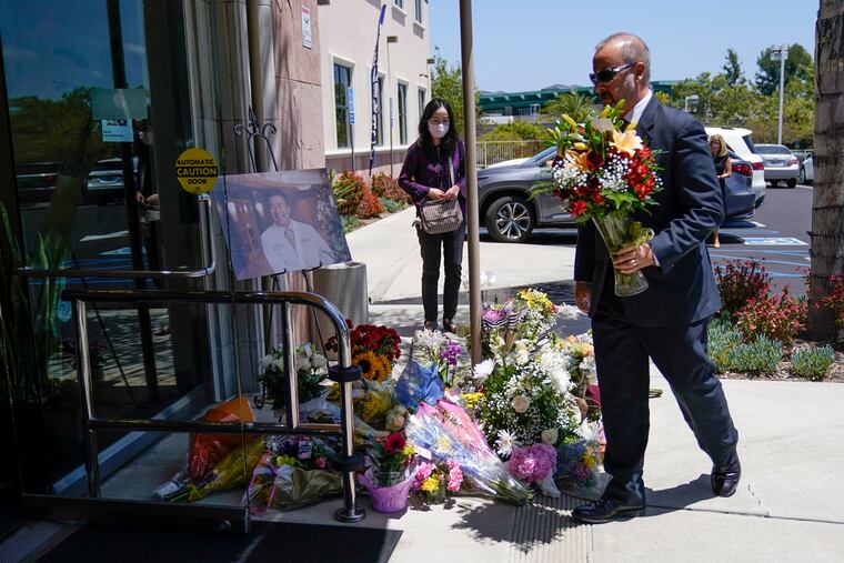 A man places flowers at a memorial honoring Dr. John Cheng sits outside his office building in Aliso Viejo, Calif. Cheng, 52, was killed in Sunday's shooting at Geneva Presbyterian Church.