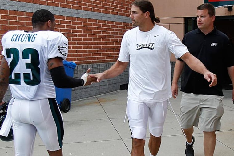 Patrick Chung, left, greets Riley Cooper, center, as he walks with Derek Boyko, right, Director of Football Media Services, on his way to speak with reporters after training camp. (David MaialettiI/Staff Photographer)