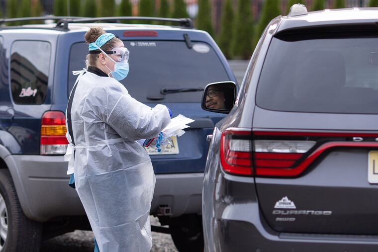 A man speaks with a Cooper Healthcare employee at a drive up COVID-19 test site in Camden on Wednesday, November 25.