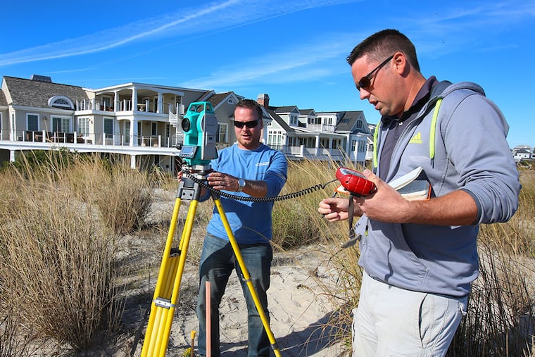 Crist Robine (left) and Brad R. Smith take measurements on the beach in Avalon. (TOM BRIGLIA/For The Inquirer)