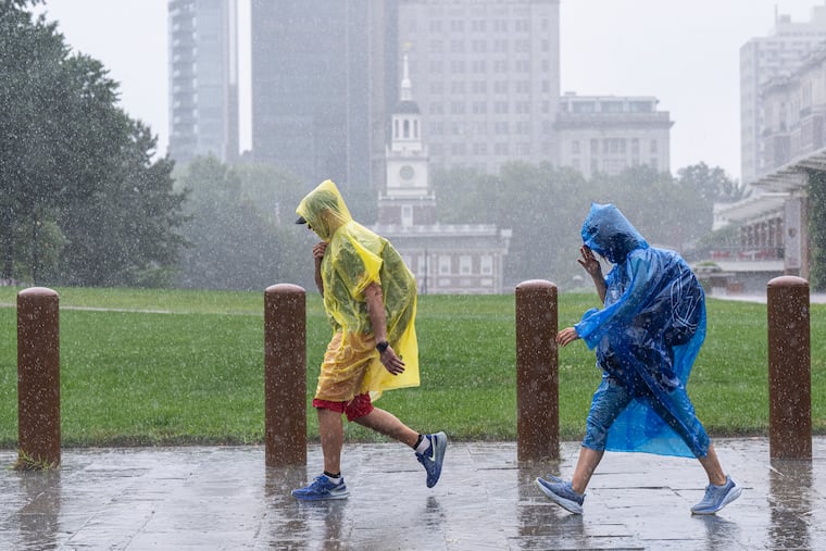 Pedestrians wearing ponchos walk along the 500 block of Arch Street near Independence Mall during the Wednesday downpour.