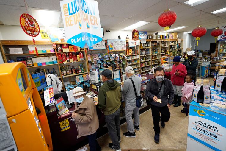 Madeline Copper, second from right, and her granddaughter, Lay-Lonnie, 5, stand in line to buy Powerball lottery tickets at the Wo Won Mini market in the Chinatown district of Los Angeles, Monday.