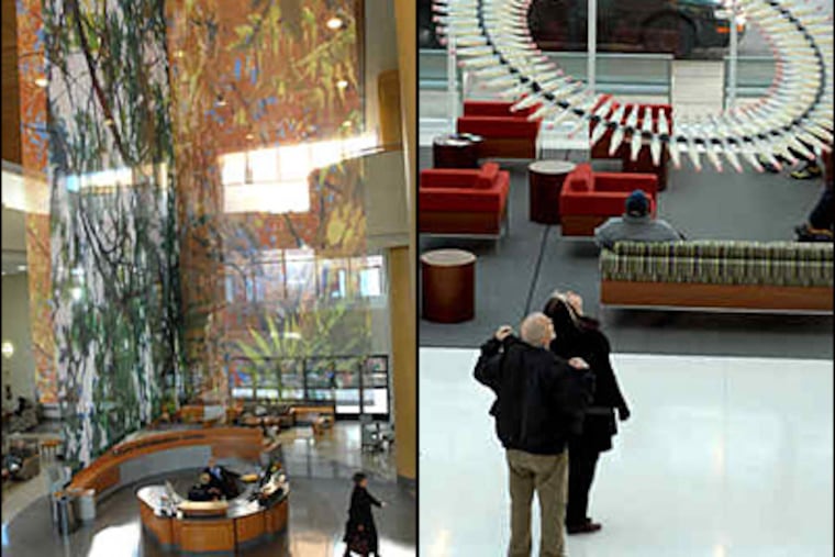 Fabric mobiles with nature motifs decorate the atrium of the Pavilion at Paoli Hospital. At right, Richard Kraus and Christine Kephart of Toms River, N.J., gaze at a Donald Lipski sculpture in the Perelman Center for Advanced Medicine in University City. (April Saul / Tom Gralish / Staff)