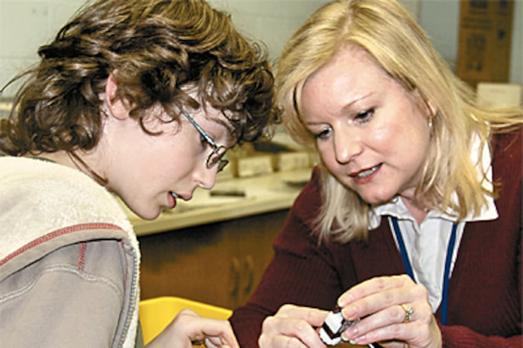 Thirteen percent of Cheltenham Township students are classified as gifted. Beth Kenna (right) works with a student in her gifted class, building a solar-powered car at Cedarwood Middle School. (John Costello/Inquirer)