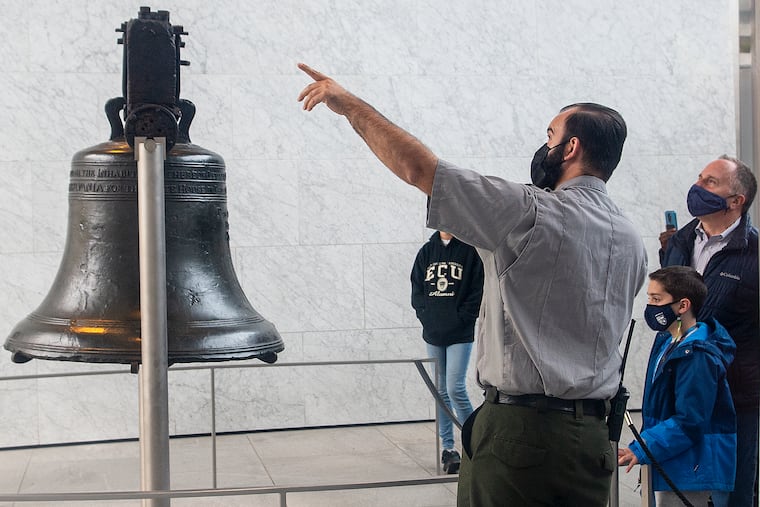 Visitors wearing masks look at the Liberty Bell on Monday, April 18, at Independence Hall in Philadelphia.