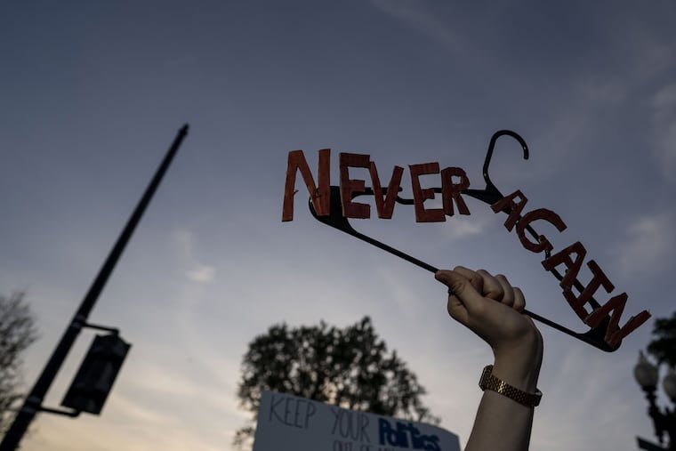 A protester holds a hanger that says "Never Again" as abortion rights demonstrators gather in front of the Supreme Court of the United States on Tuesday, May 3, 2022, in Washington, D.C.