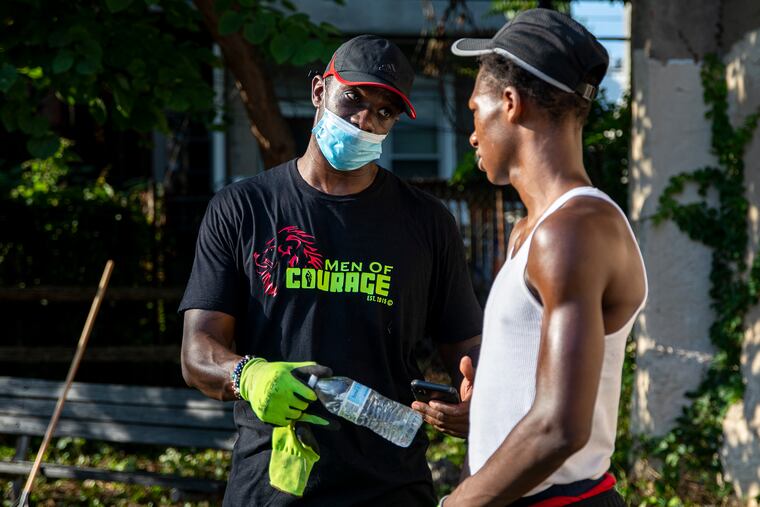 Taj Murdock (left), one of the main organizers with the Black Brotherly Love group, reaches out to Shakur Smith, 17, a volunteer, to talk about long-term goals and his career path during a cleanup event at the West Mill Creek Playground.