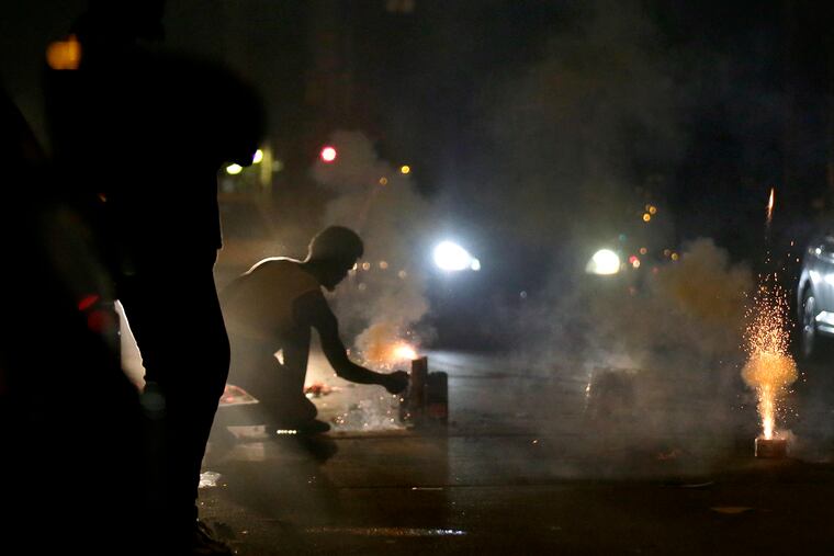 A car waits for fireworks to go off before passing through on 22nd Street near Norris in North Philadelphia in June.