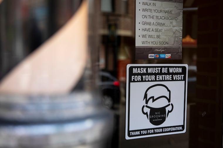 A sign on Nic Grooming Barbershop on 20th Street in Philadelphia requires customers to wear a mask as they enter and get a haircut.
