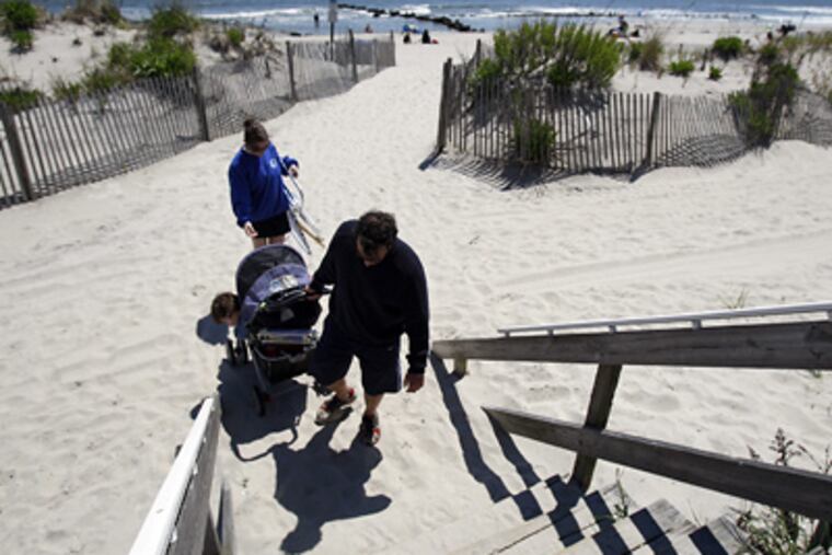 Kevin Morgan and his wife, Amy, leave Ocean City’s beach yesterday. Eight miles long and well-maintained, the beach has been rated No. 1 by visitors and coastal scientists. (David Maialetti / Staff Photographer)