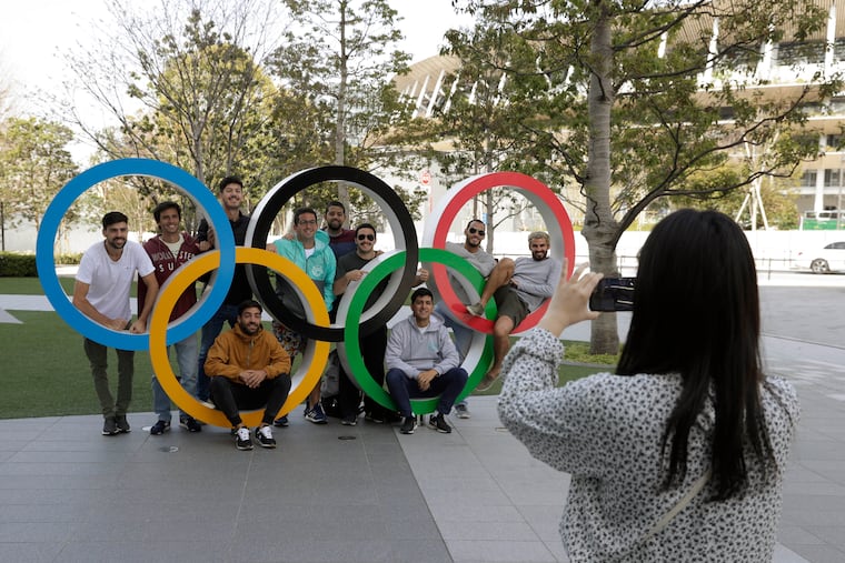 A group of students from Uruguay pose for a souvenir picture on the Olympic Rings set outside the Olympic Stadium in Tokyo.