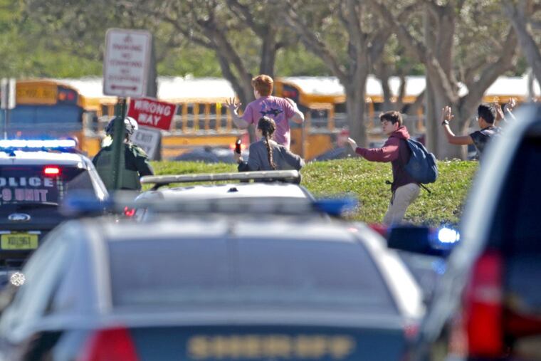 Students run wth their hands in the air outside of Stoneman Douglas High School in Parkland, Fla. after reports of an active shooter on Wednesday, Feb. 14, 2018.