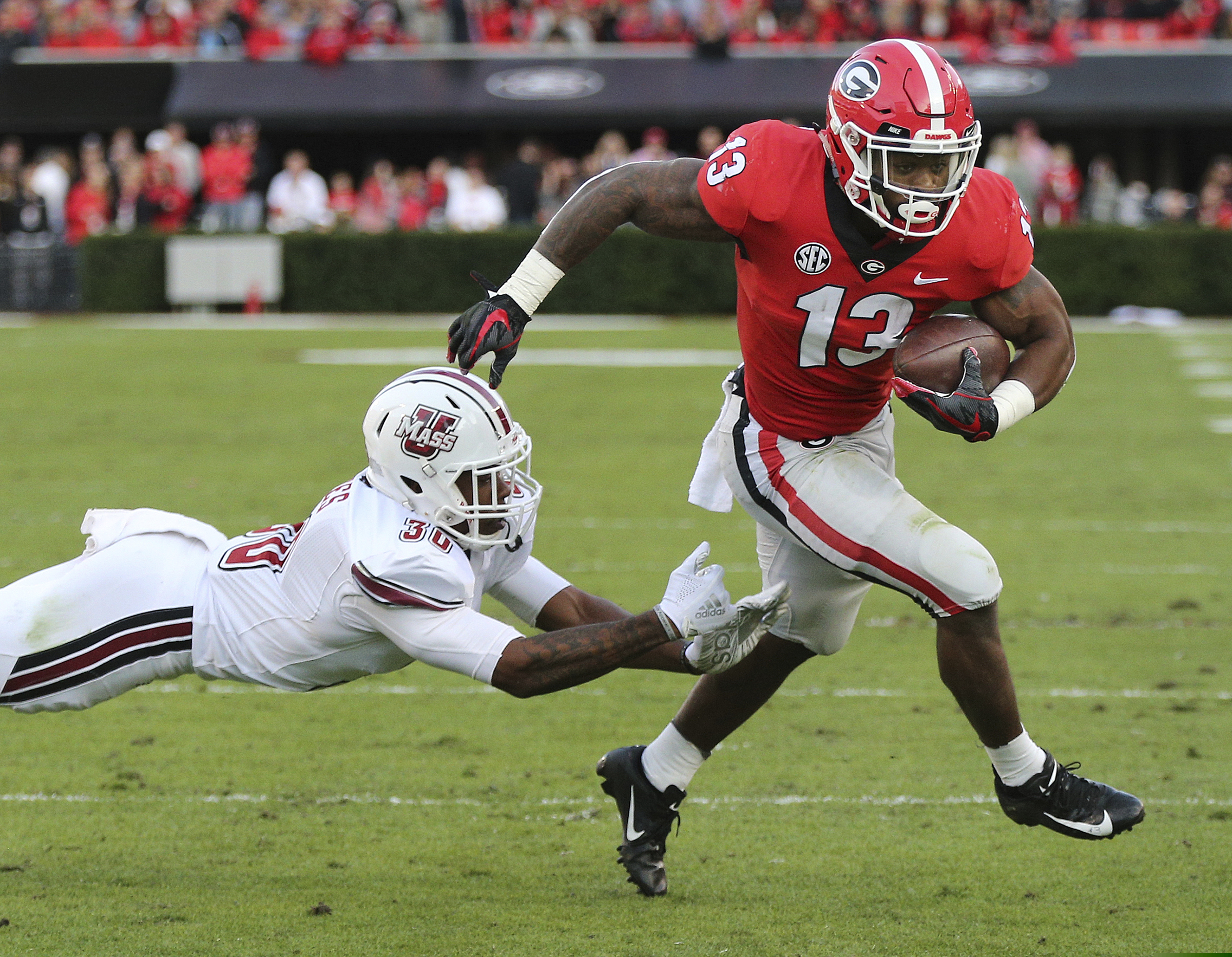 Georgia tailback Elijah Holyfield breaks away from Massachusetts safety Tyler Hayes for a touchdown during the first half of an NCAA college football game, Saturday, Nov. 17, 2018, in Athens, Ga. (Curtis Compton/Atlanta Journal-Constitution via AP)