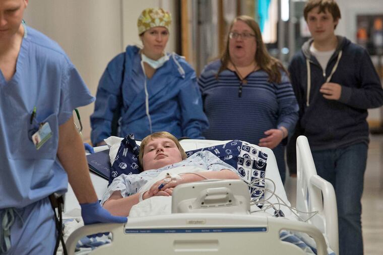 Landon is wheeled into surgery at Children's Hospital with his mother, Amy, and brother Logan near. Logan, 15, has a similar heart condition and had a different type of implant three years ago.