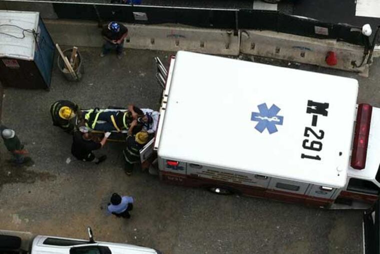 A man injured in a fall at a construction site at 15th and Arch streets in Center City is put into an ambulance.
