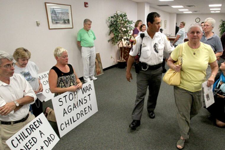 The Pro-Life Coalition of Pennsylvania holds a "pray-in" to protest same-sex marriage licenses in the Montgomery County Court House July 26, 2013 as a security agent escorts Lynn Zeitlin, 2nd from right, and Gabriele Assagioli, right, who received their marriage license. ( CHARLES FOX / Staff Photographer )