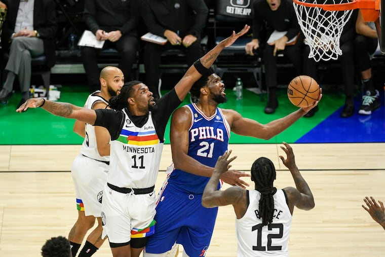 Philadelphia 76ers center Joel Embiid (21) goes up for a shot past Minnesota Timberwolves center Naz Reid (11) on Tuesday.