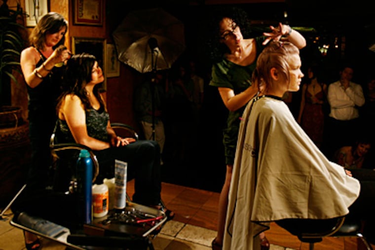 Stylist Bronwen Melvin (far left) cuts Kaitlin Wines' hair, while Danielle George styles Deanna Young's tresses .