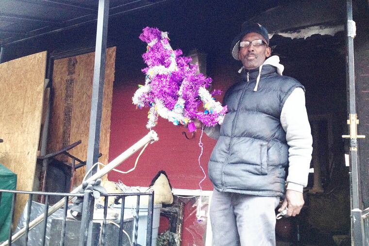 An East Germantown grandfather who identified himself only as Danny holds his family's damaged Christmas tree on his front porch after police say was an arson fire set by someone early Sunday damaged their home on Coulter Street. (Morgan Zalot / Daily News staff)
