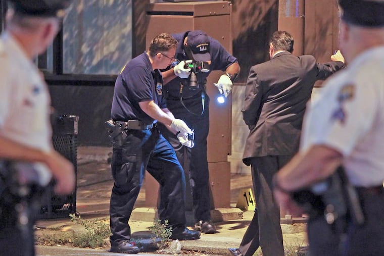 Investigators gather on Torresdale Avenue near Magee Avenue in the Tacony section of Philadelphia on Tuesday Aug. 19, 2014, after a Philadelphia police officer was wounded during an exchanged of gunfire with a suspect. (For the Daily News/ Joseph Kaczmarek)