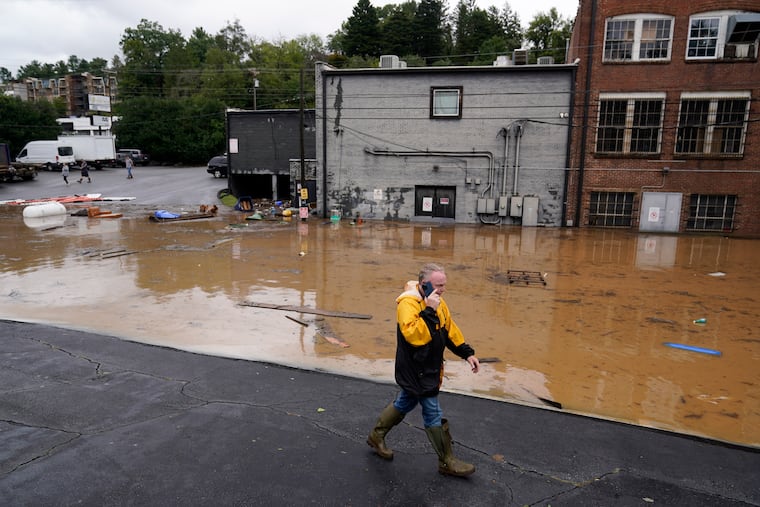 A man walks near a flooded area near the Swannanoa river, effects from Hurricane Helene , Friday, Sept. 27, 2024, in Asheville, N.C.