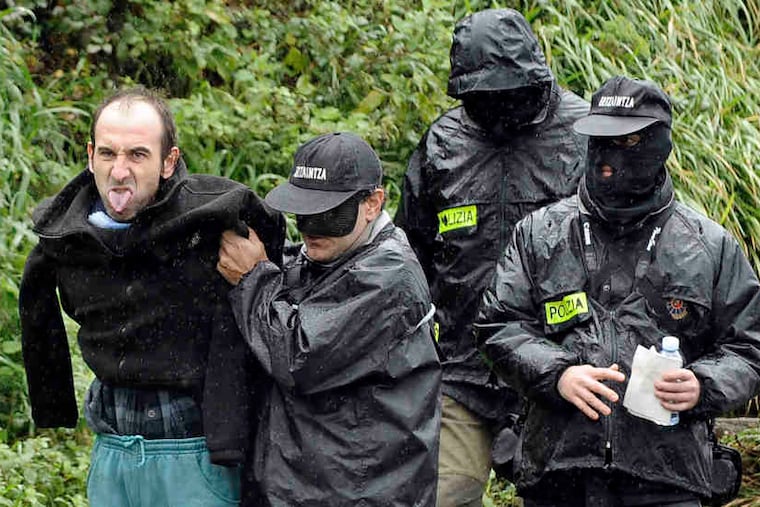 Police leading away Ibon Iparragirre, an alleged ETA chief , in January. Some are waiting to see if ETA renounces violence for good.