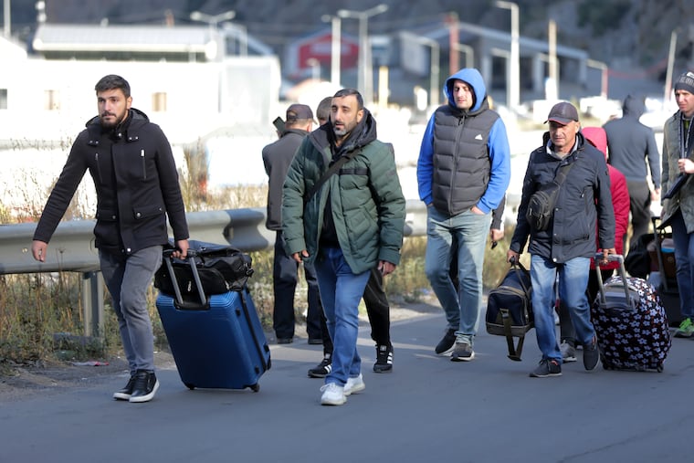 A group of Russians walk after crossing the border at Verkhny Lars between Georgia and Russia in Georgia, Tuesday, Sept. 27, 2022. Long lines of vehicles have formed at a border crossing between Russia's North Ossetia region and Georgia after Moscow announced a partial military mobilization.